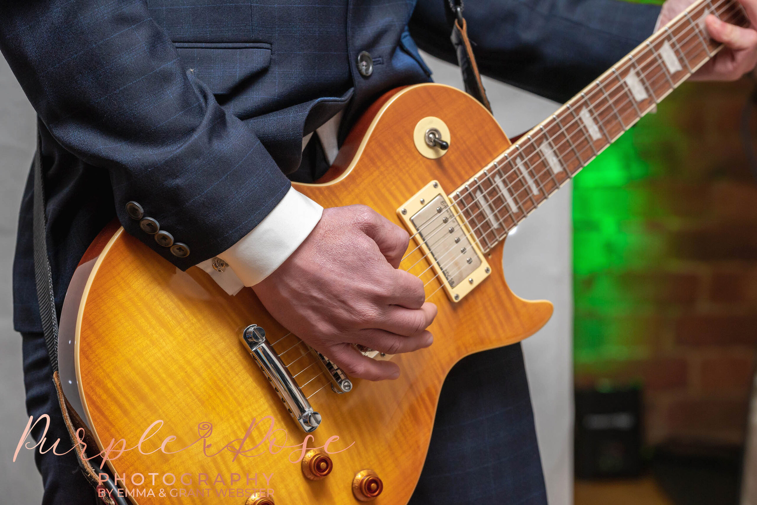 CLose up of a grooms hand as he plasy the guitar on his wedding day in Milton Keynes