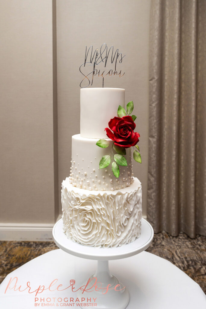 Photo of a white wedding cake with a red flower in Milton Keynes