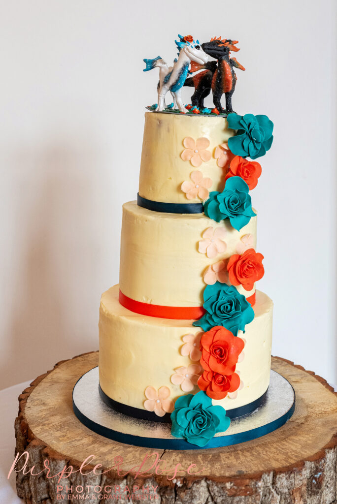 Photo of three tier wedding cake with orange and blue flowers at a wedding in Buckinghamshire