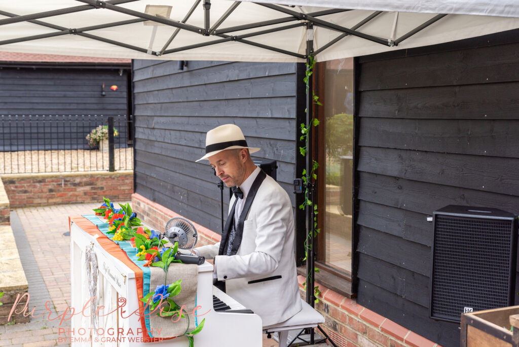 Photo of a man in a white hat and suit playing a piano at a wedding in Milton Keynes