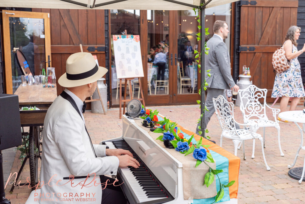 Photo of a man in a white hat and suit playing a piano at a wedding in Milton Keynes