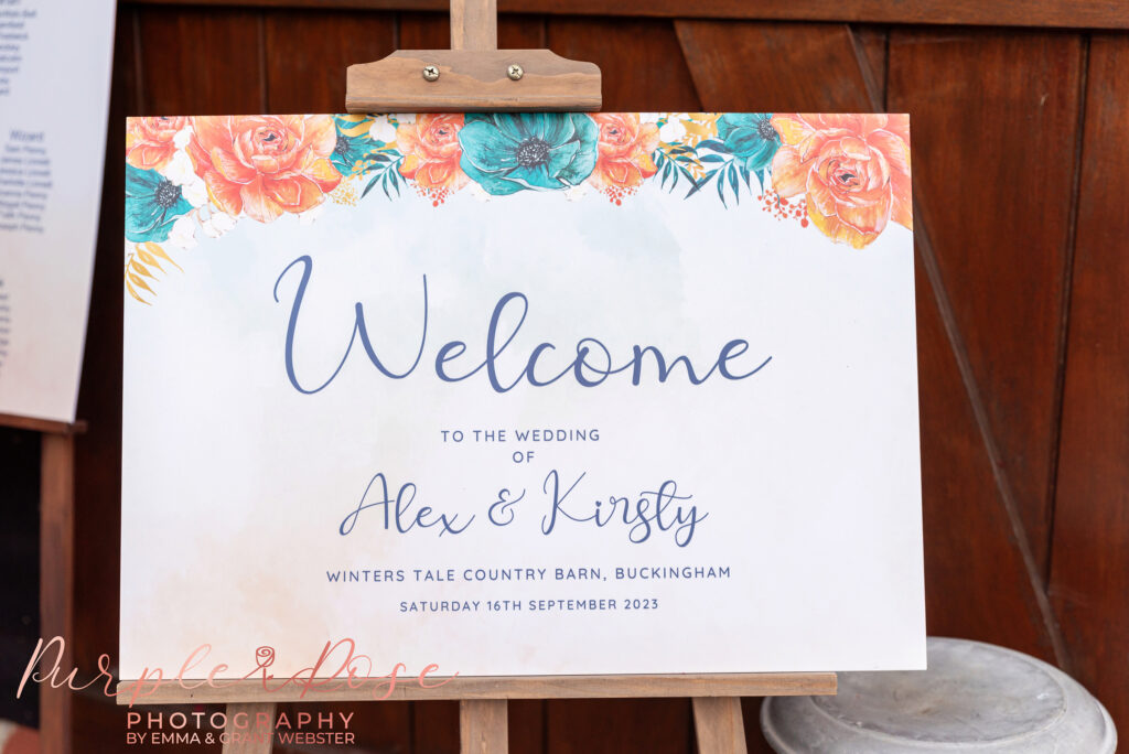 Photo of an orange and blue themed welcome to out wedding sign at a wedding in Milton Keynes