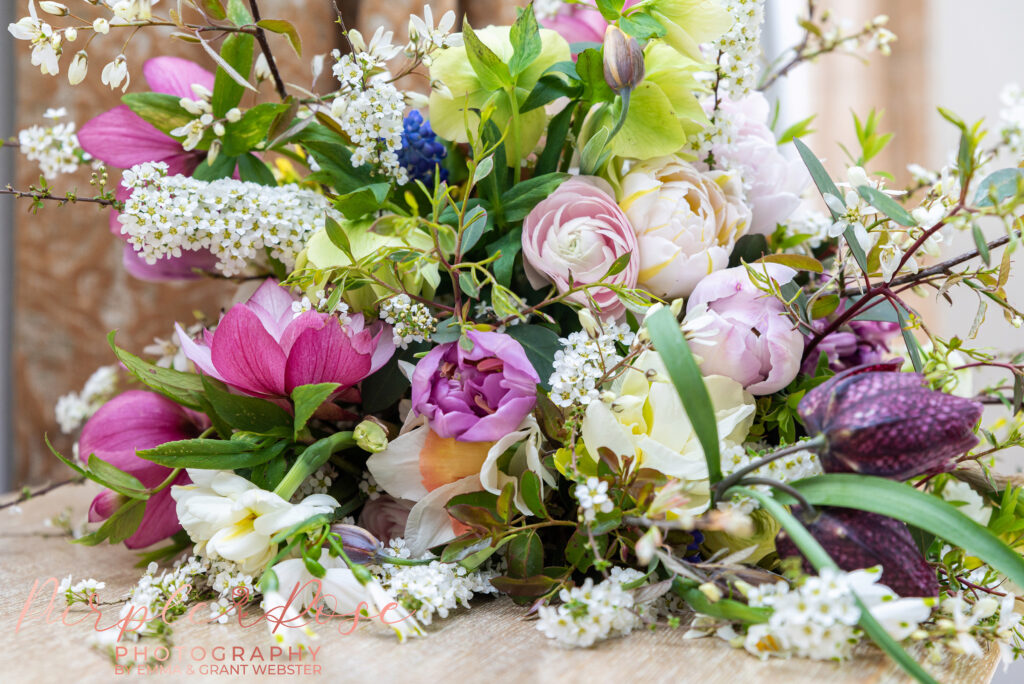 Photo of a brides floral bouquet laid down on a reflective table in Fawsley Hall Daventry