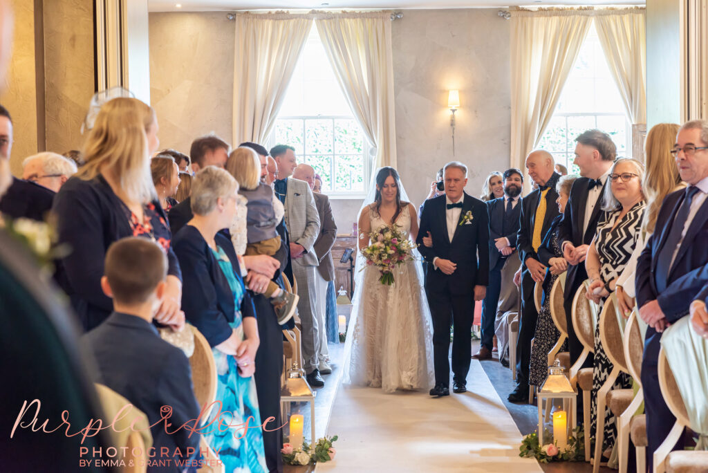 Photo of a bride and her father walking to the wedding ceremony at her wedding in Northampton