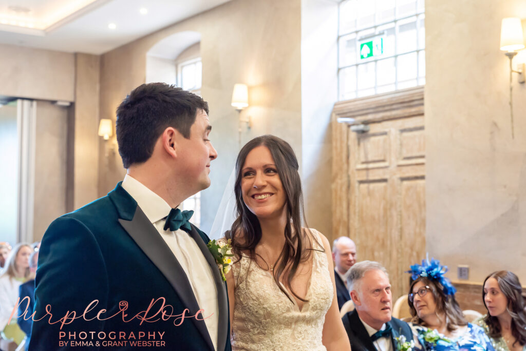 Photo of a bride and groom smiling at each other during their wedding ceremony in Northampton