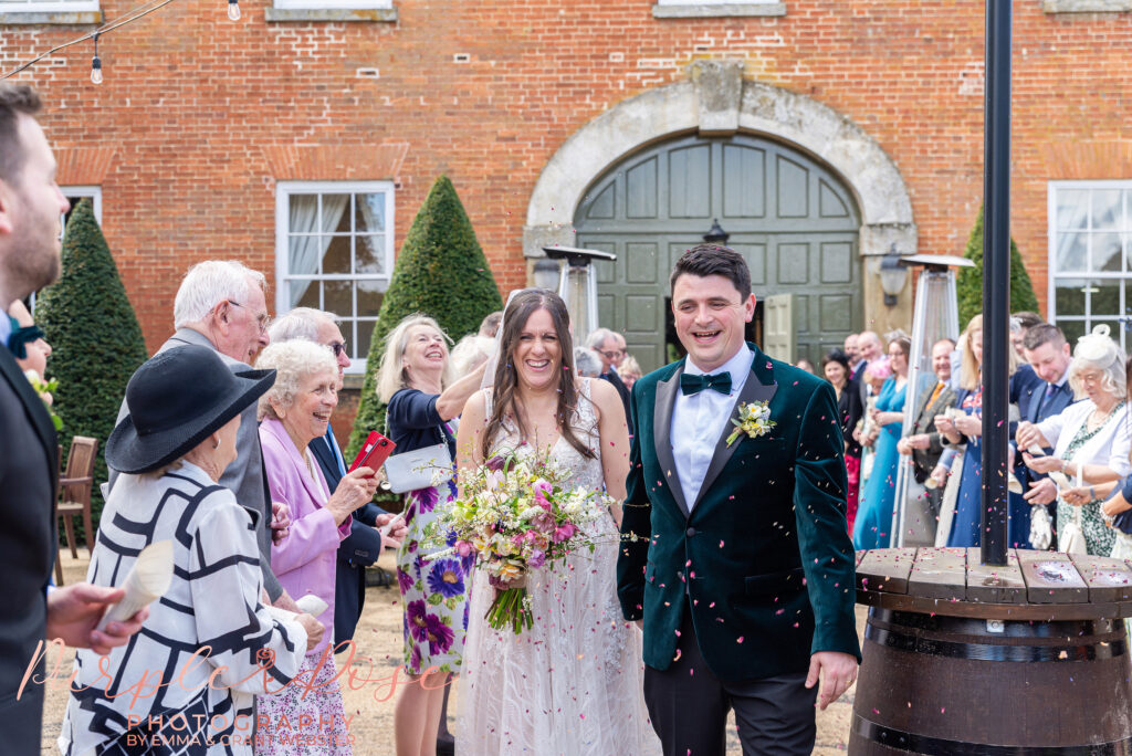 Photo of a bride and groom walking through a confetti tunnel on their wedding day in Northampton