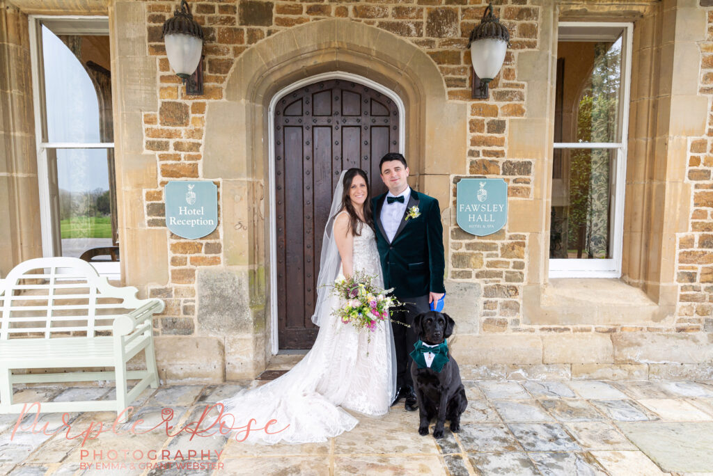 Photo of bride, groom and their dog outside their wedding venue in Northampton