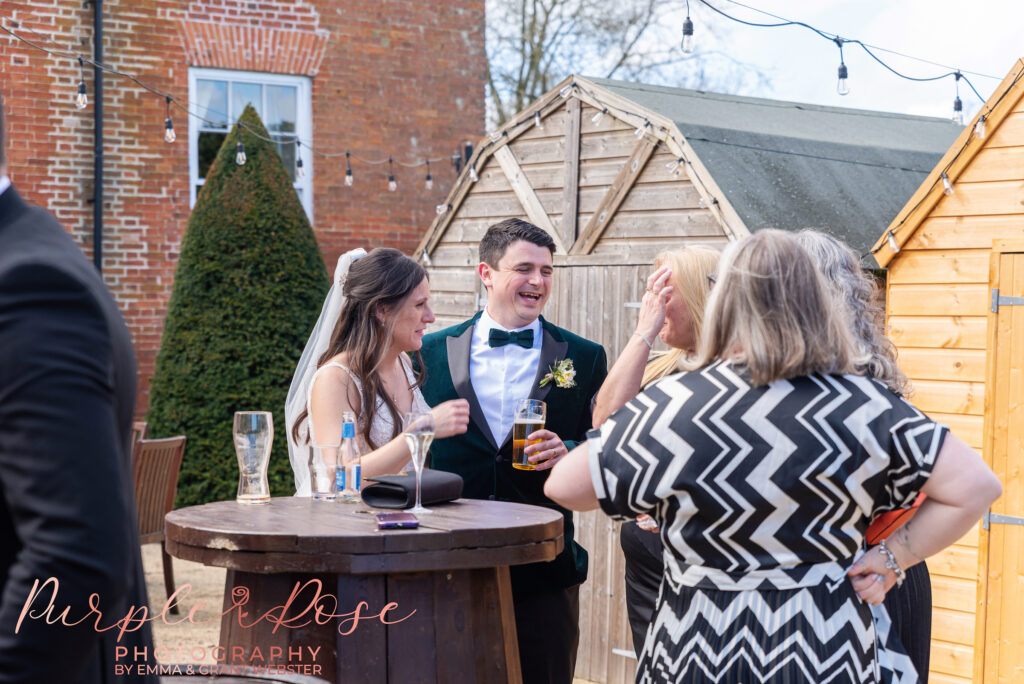 Photo of a bride and groom laughing with their wedding guests