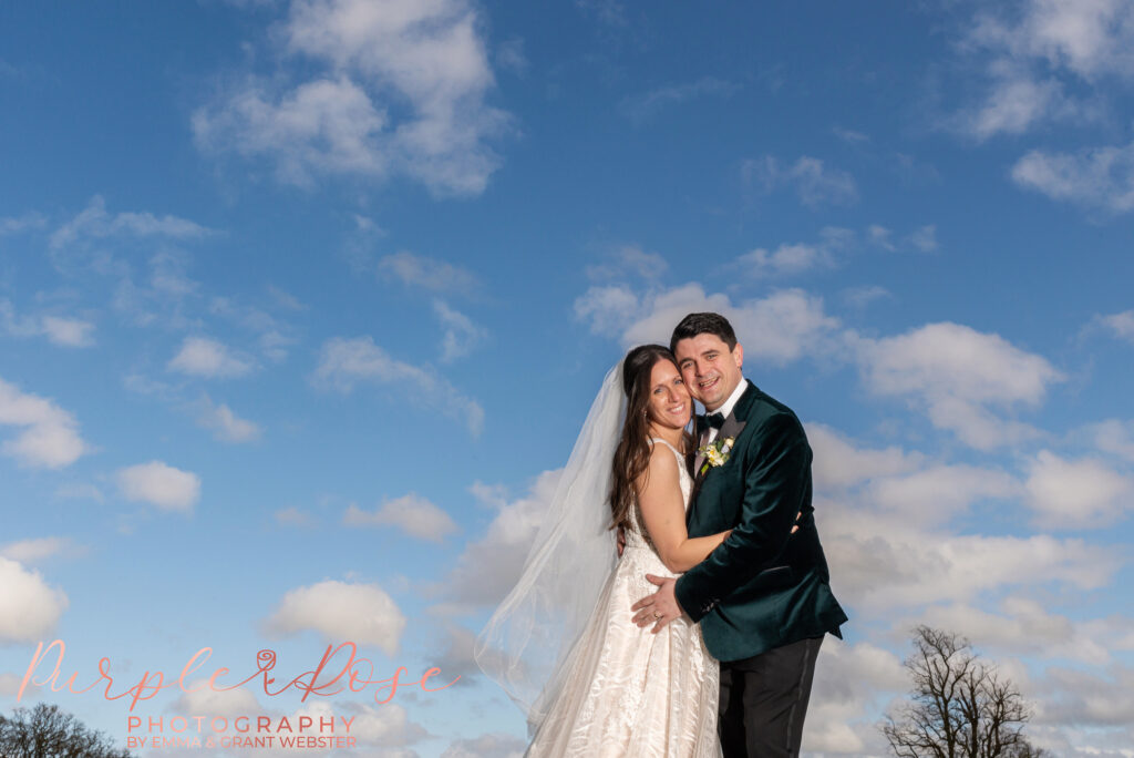 Photo of a bride and groom in front of a cloud filled sky on their wedding day in Northampton