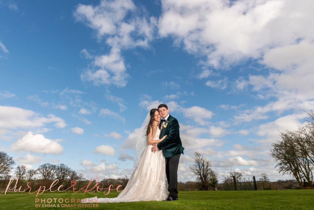 Photo of a bride and groom in front of a cloud filled sky on their wedding day in Northampton