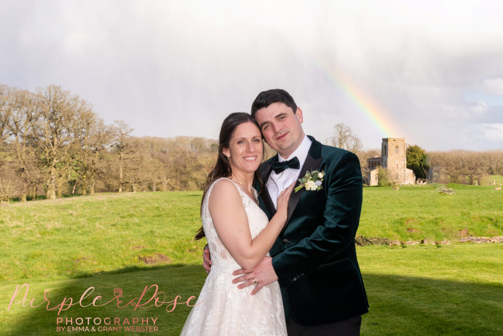 Photo of a bride and groom in front of rainbow on their wedding day in Northampton