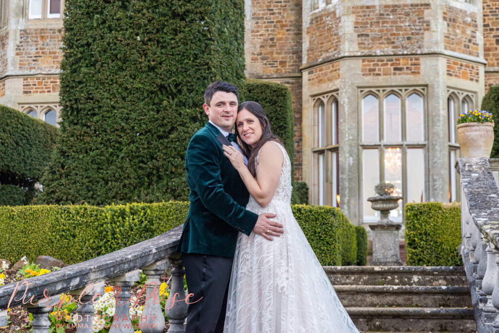 Photo of a bride and groom leaning on a banister of a staircase outside their wedding venue in Northampton 