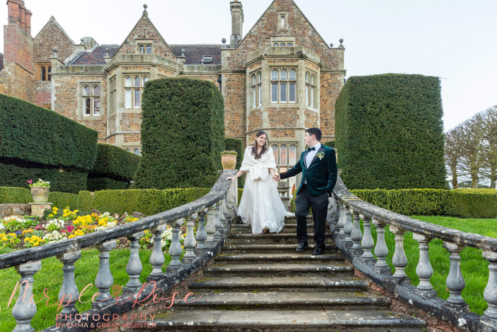 Photo of a bride and groom walking down a staircase outside their wedding venue in Northampton