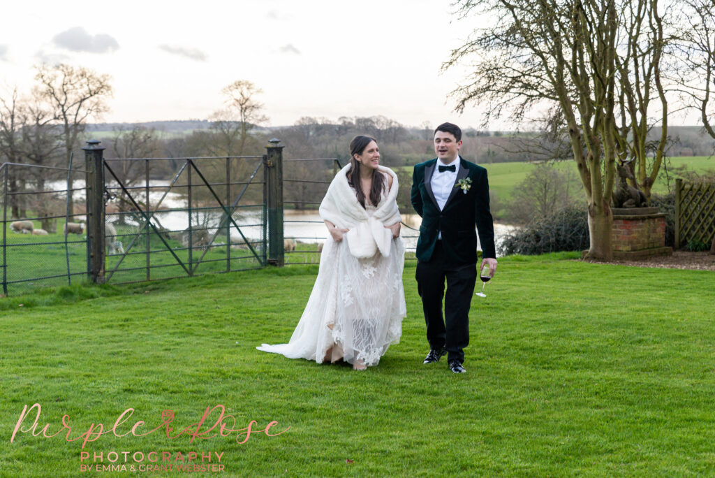 Photo of a bride and groom walking in the grounds of their wedding venue