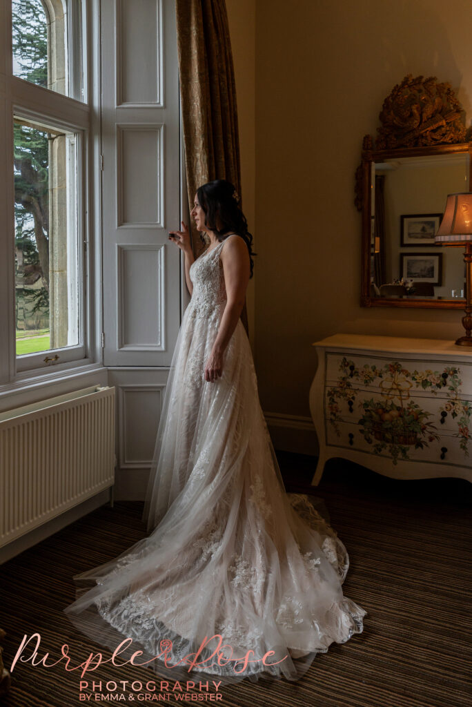 Photo of a bride leaning on a window on her wedding day in Northampton