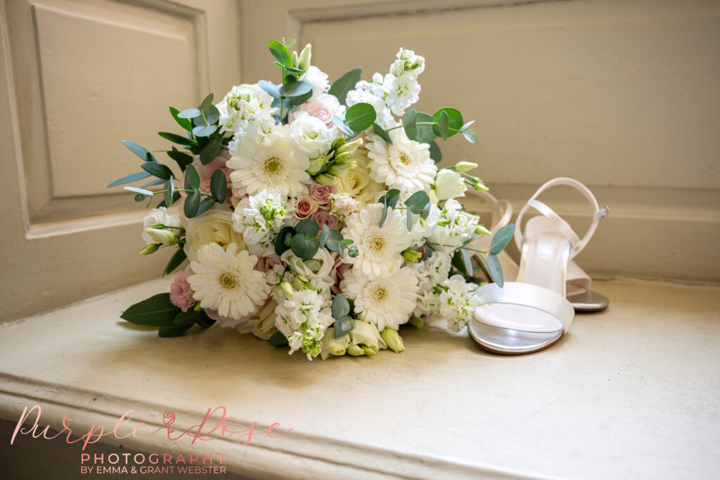 Photo of a brides bouquet and wedding shoes in a bay window at Chicheley Hall