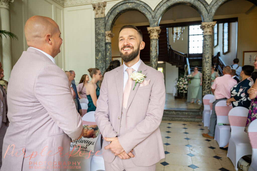 Groom smiling nervously as he waits for his bride to arrive at their wedding ceremony at Chicheley Hall Milton Keynes