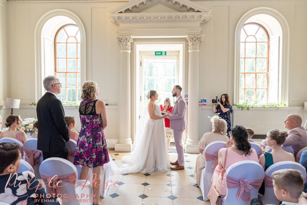 Bride and groom facing each other surrounded by their wedding guests on their wedding day at Chicheley Hall in Milton Keynes