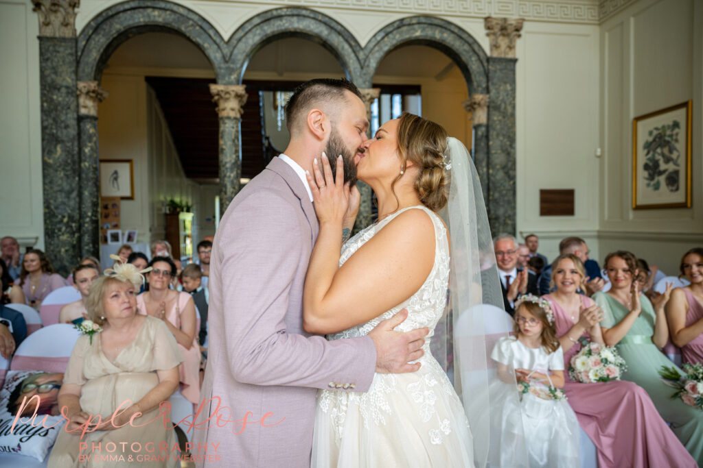 Bride and groom sharing their first kiss at their wedding ceremony at Chicheley Hall in Milton Keynes