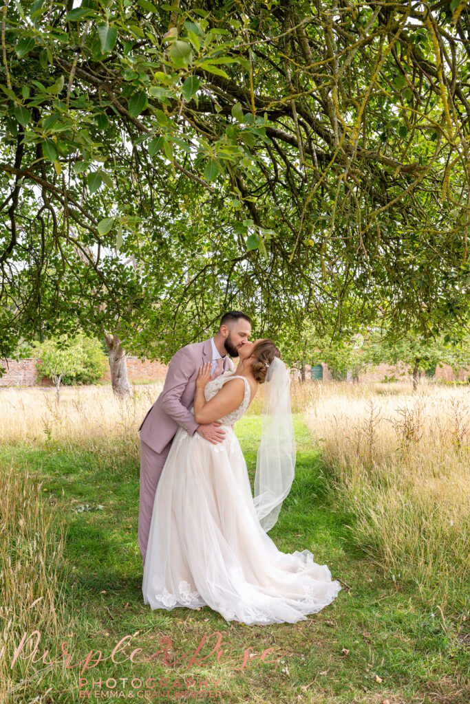Photo of a bride and groom kissing in the gardens at Chicheley Hall on their wedding day in Milton Keynes