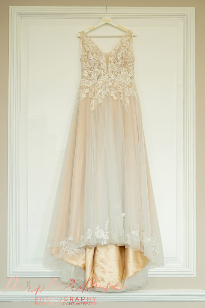 Brides wedding dress hanging on a wall in Chicheley Hall in Milton Keynes