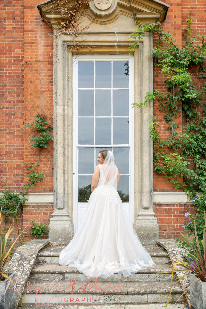 Photo of a bride looking over her shoulder as her wedding dress flows behind her