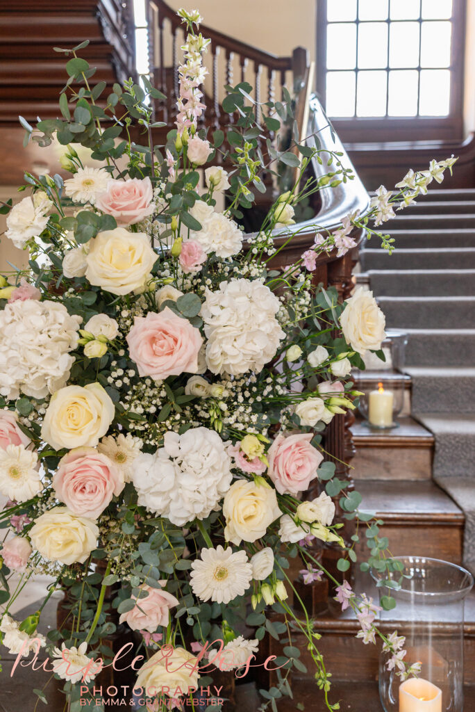 Photo of flowers going up the grand staircase at Chicheley Hall in Milton Keynes on a wedding day