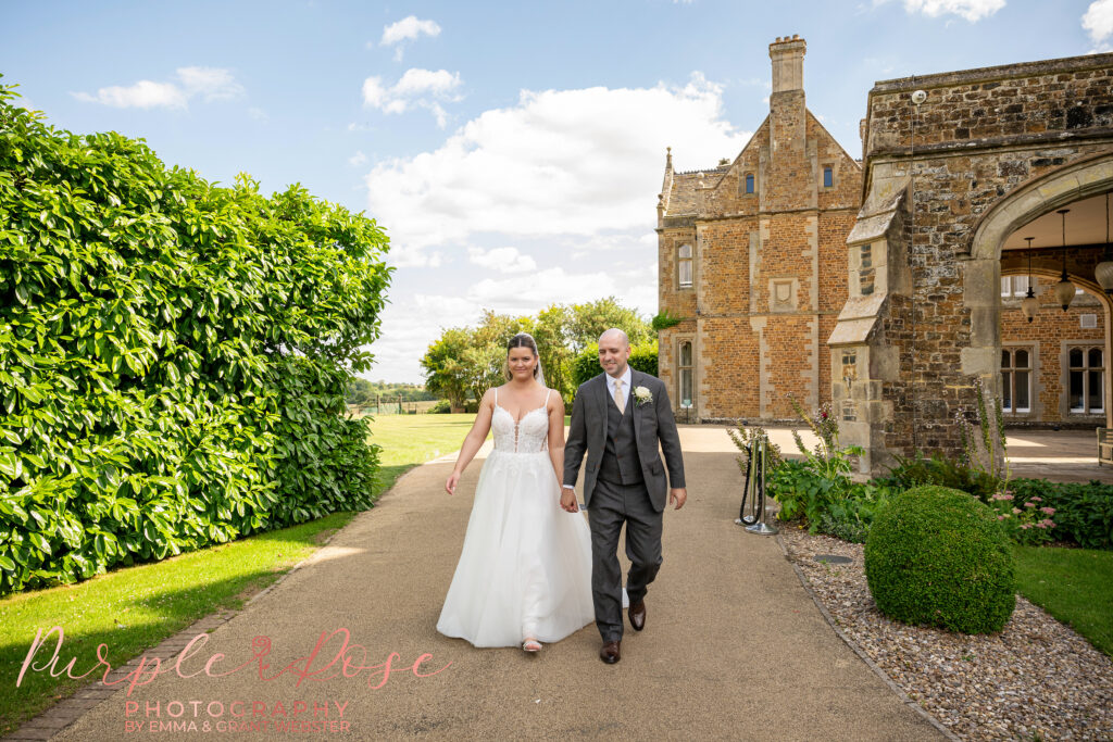 bride and groom walking hand in hand in the grounds of their wedding venue Fawsley hall