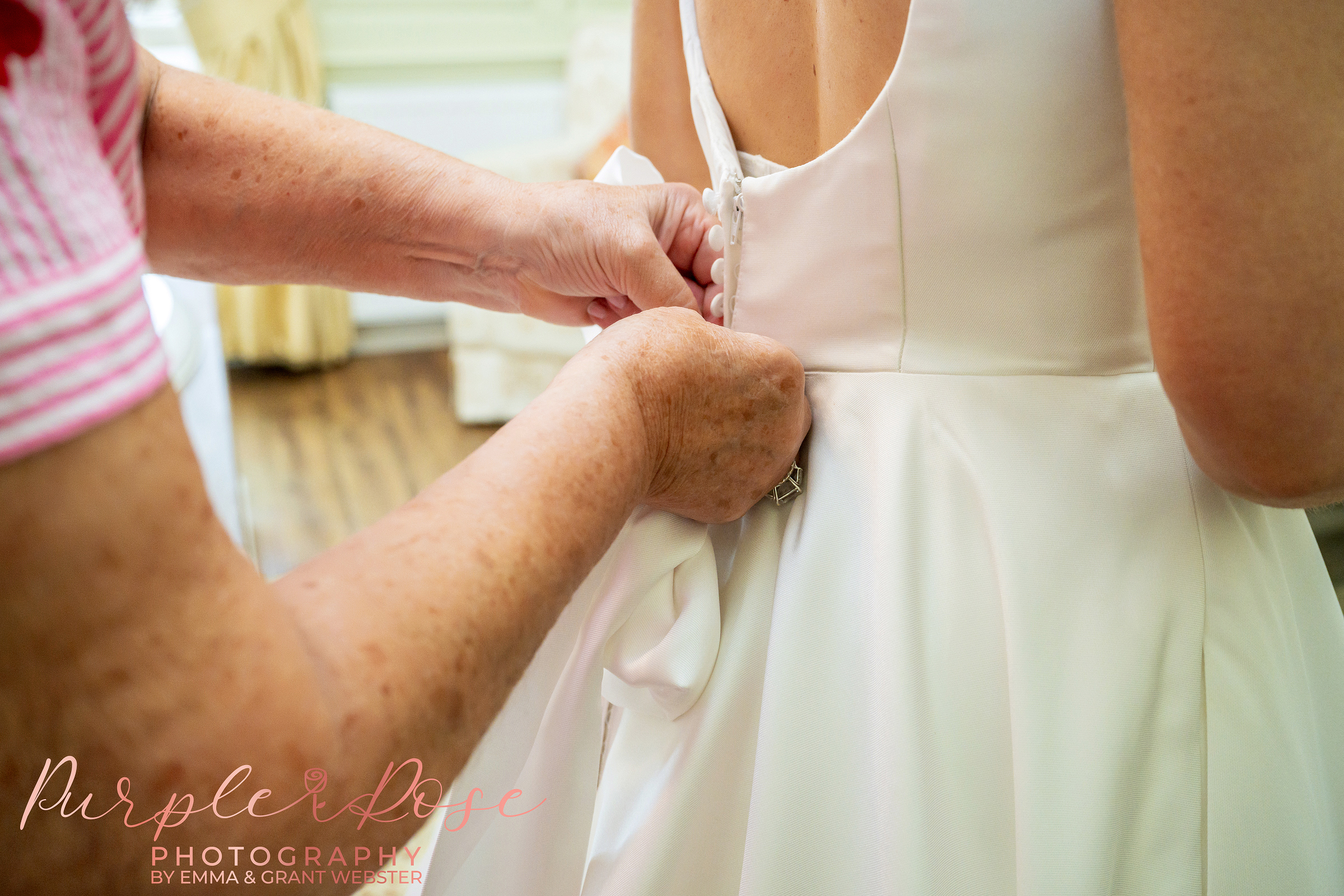 Photo of a brides dress being buttoned up on her wedding day in Northampton