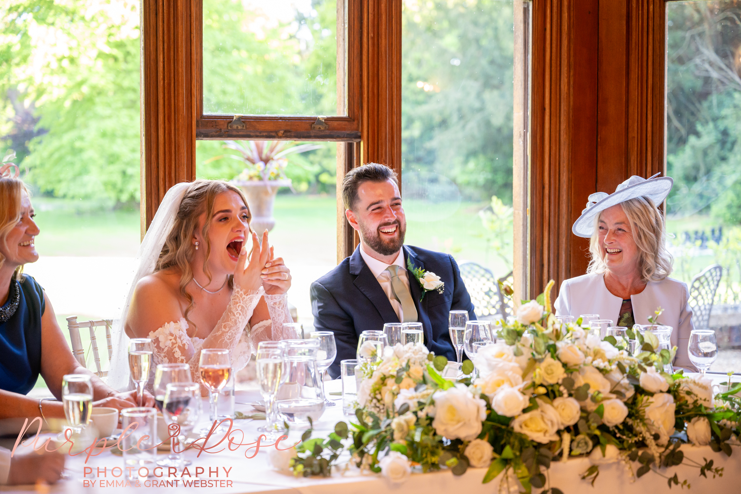 Photo of a bride and groom on their wedding day in Peterborough laughing during the wedding breakfast