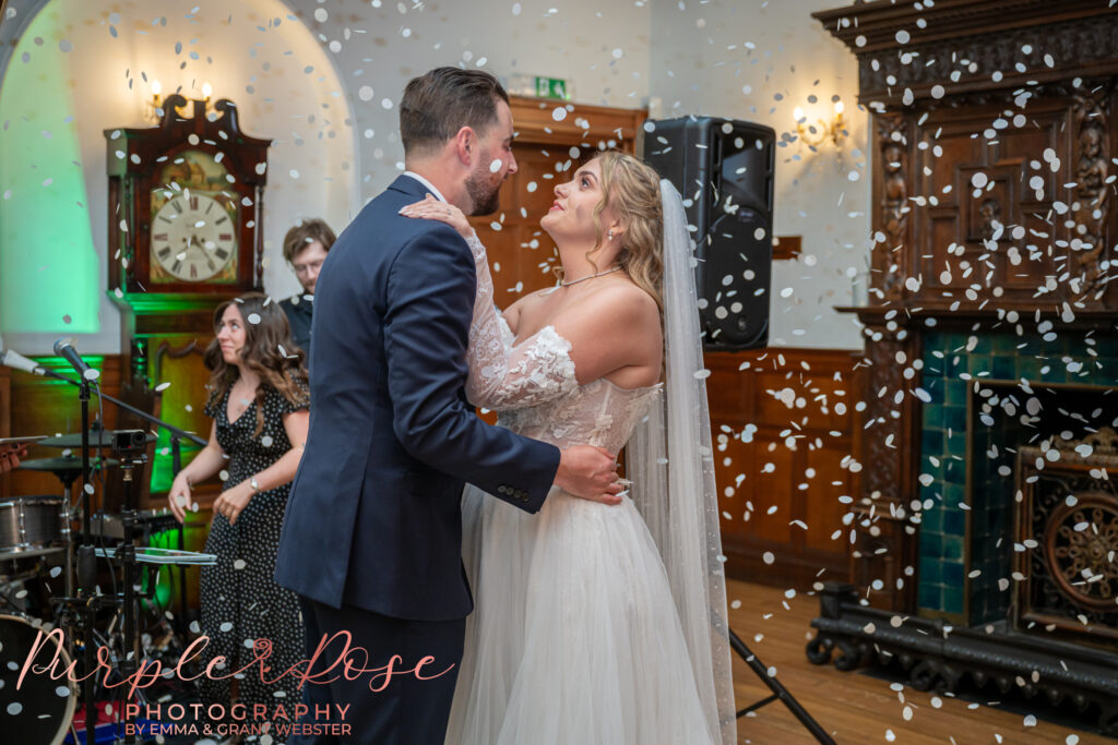 Bride and groom dancing on their wedding day as confetti falls.