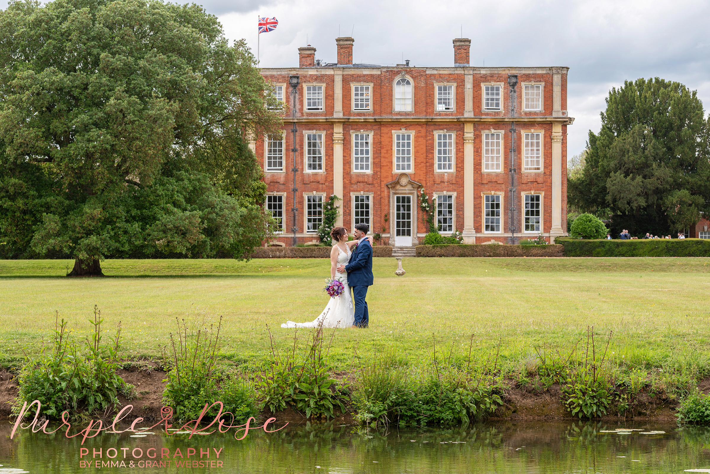 Photo of a bride and groom taken across a lake with Chicheley Hall behind them