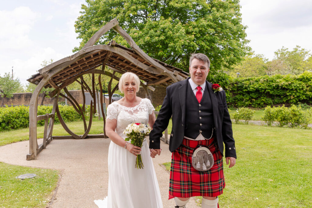 Photo of a bride and groom walking through the gardens after their wedding at Bride and groom laughing during their wedding ceremony at Milton Keynes Registry Office