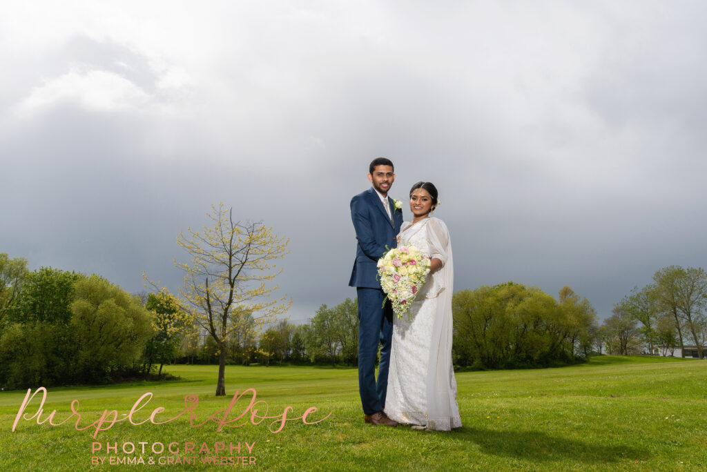 Photo of a bride and groom in front of a stormy sky after their wedding at Milton Keynes Registry Office