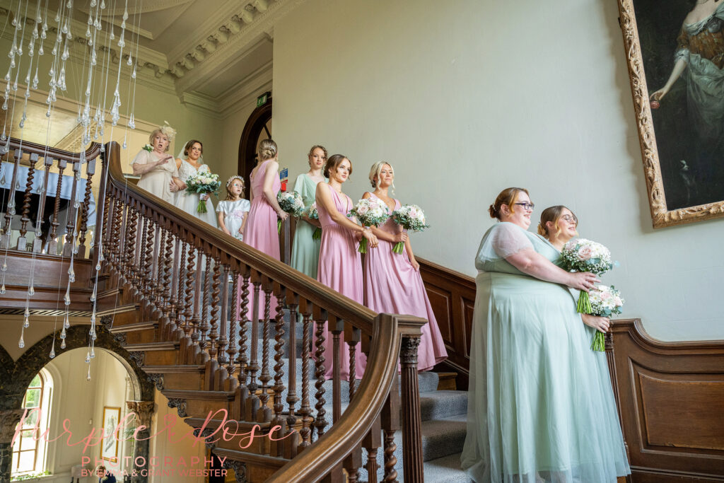 Photo of the bridal party stood on the staircase at Chicheley Hall ahead of the wedding ceremony
