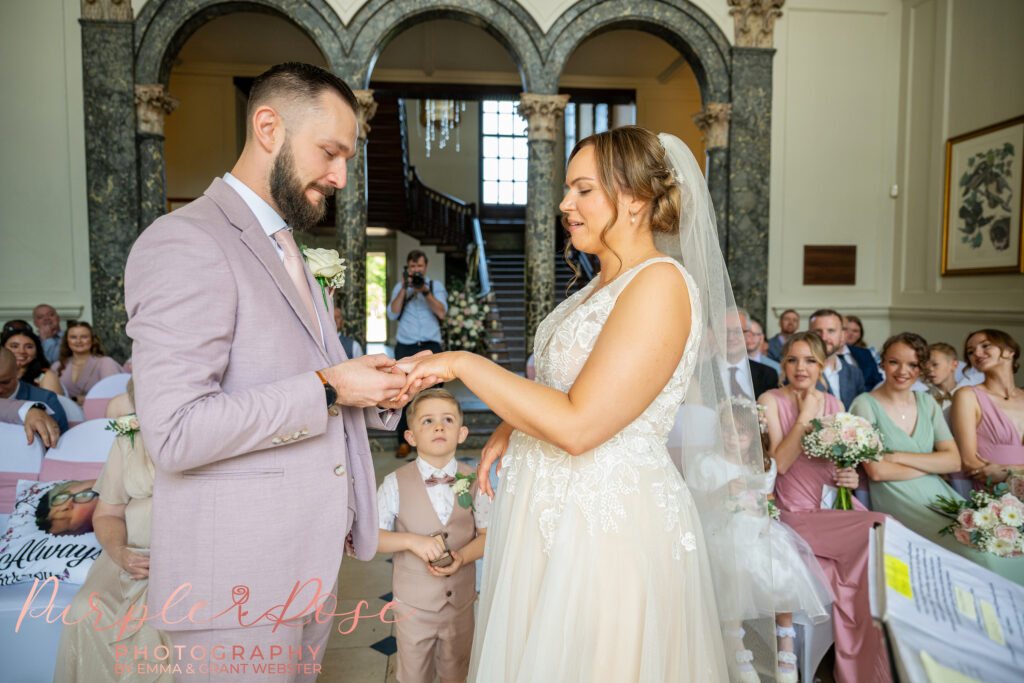 Bridal party exchanging wedding rings during their wedding ceremony at Chicheley Hall in Milton Keynes