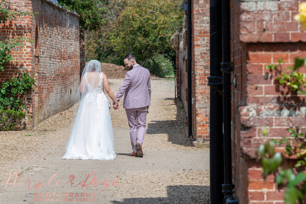 Bride and groom walking away hand in hand on their wedding day at Chicheley Hall in Milton Keynes