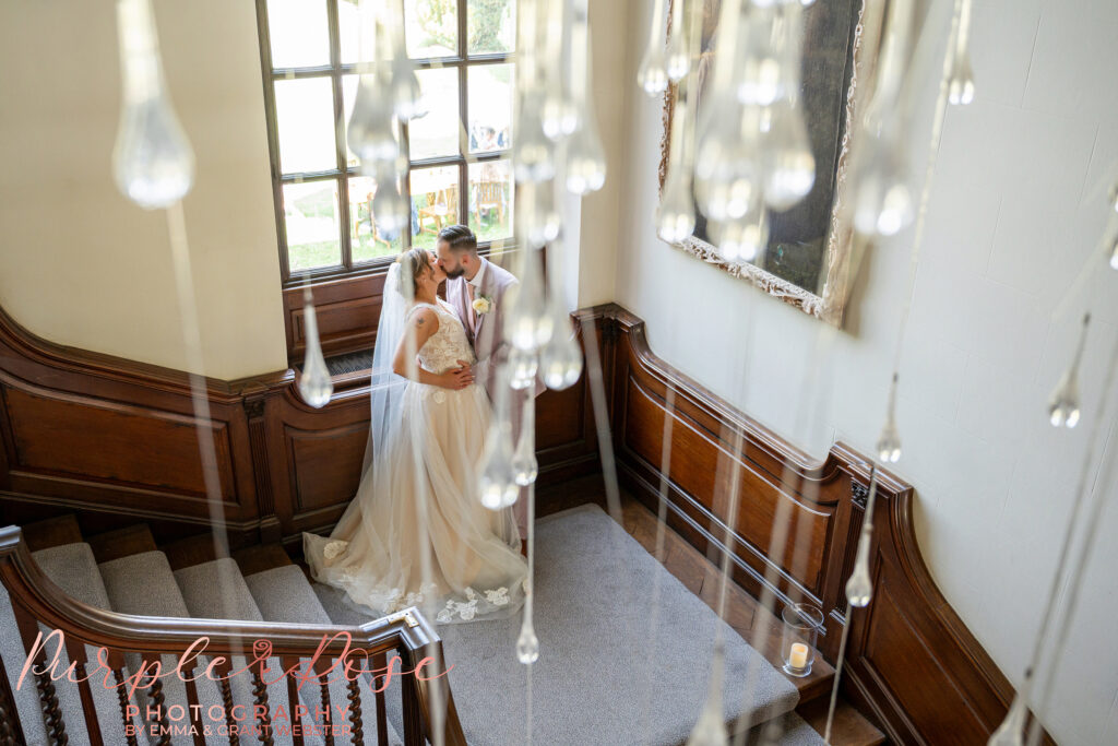 Photo of a bride and groom on their wedding day at Chicheley Hall stood on the staircase