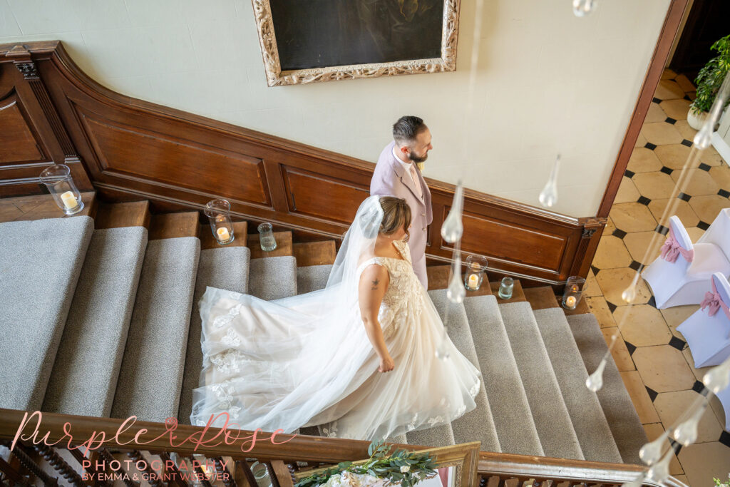 Bride and groom walking down the grand staircase on their wedding day at Chicheley Hall in Milton Keynes
