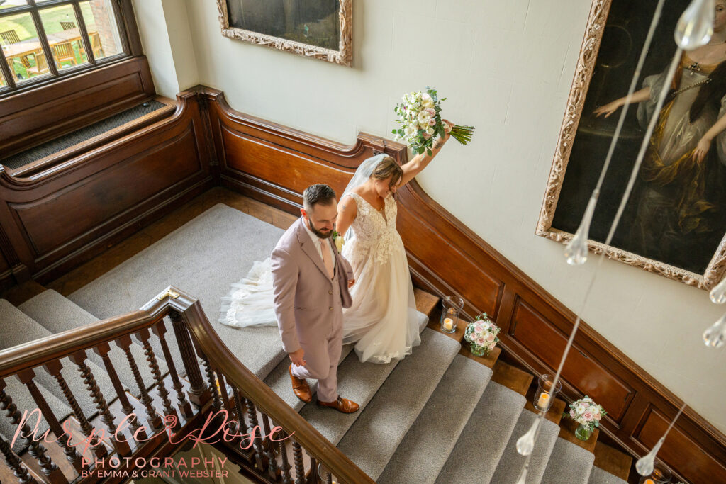 Bride and groom celebrating as they walk down the staircase at Chicheley Hall in Milton Keynes