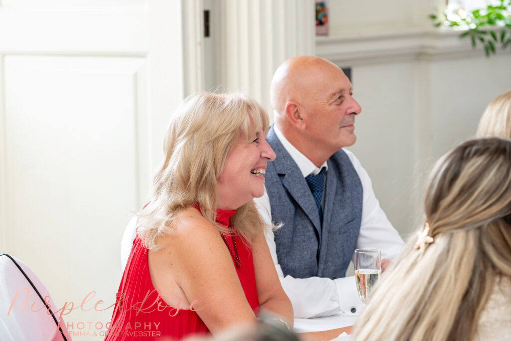 Wedding guest laughing during the speeches at a wedding at Chicheley Hall in Milton Keynes