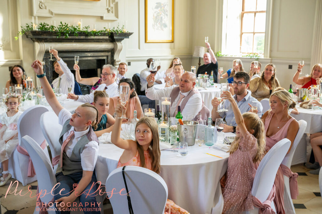 Wedding guest toasting during the speeches at Chicheley Hall in Milton Keynes