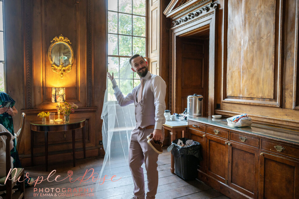 Groom wearing his brides veil on their wedding day at Chicheley Hall in Milton Keynes