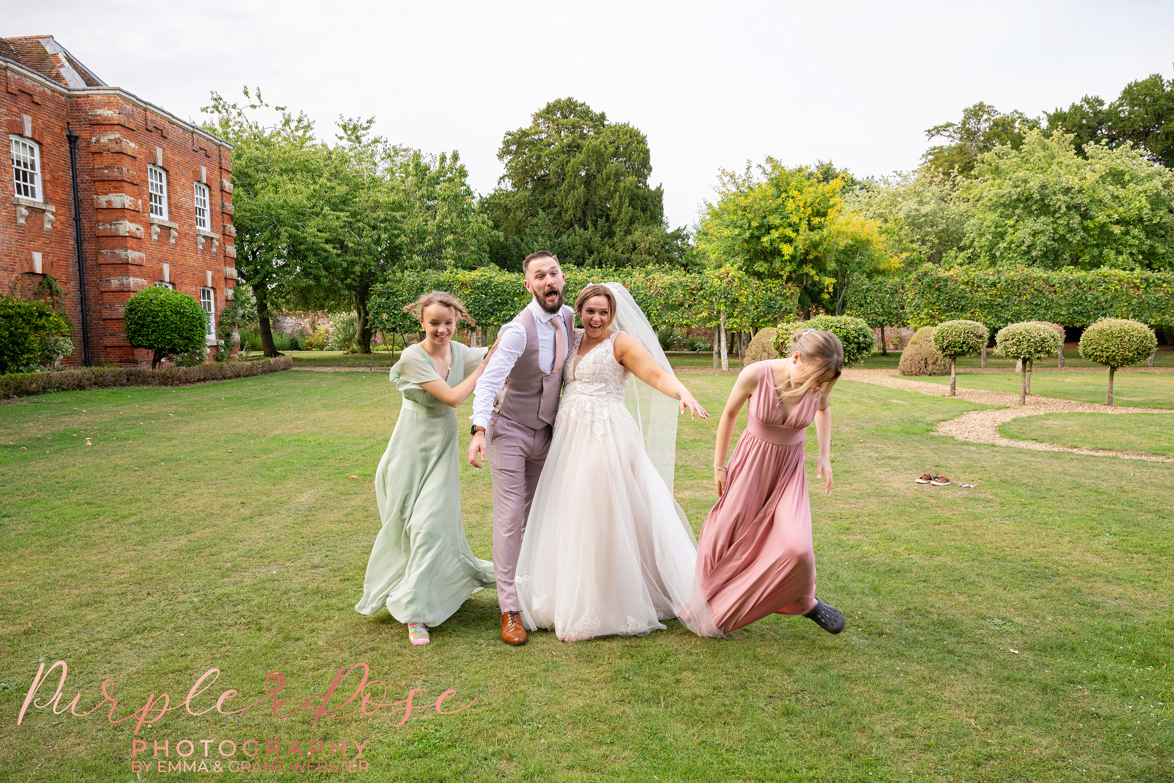 Bride and groom laughing as their children sneak up on them at Chicheley Hall in Milton Keynes