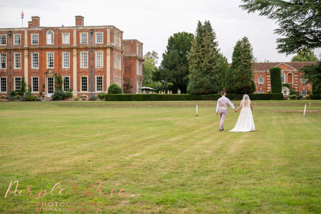 Bride and groom walking away hand in hand at their wedding day at Chicheley Hall in Milton Keynes