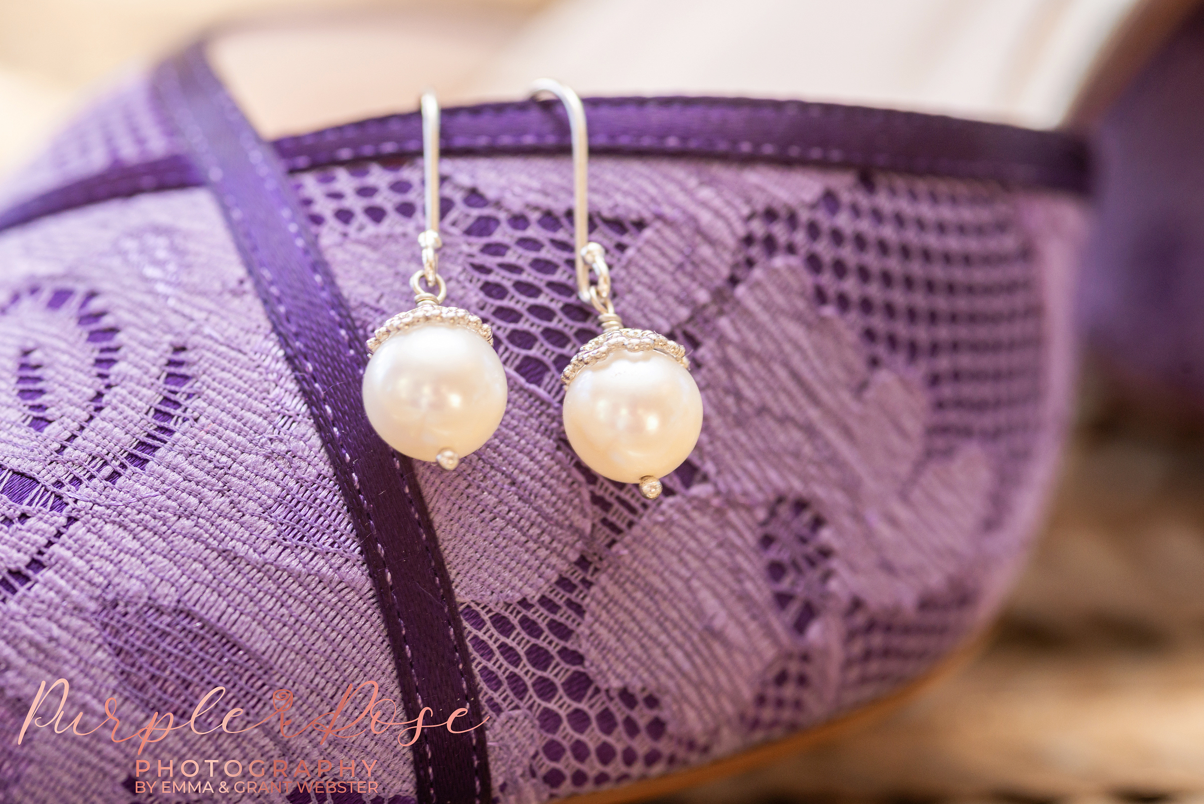Close up photo of a brides pearl ear rings hanging on her purple wedding shoes in Northamptonshire