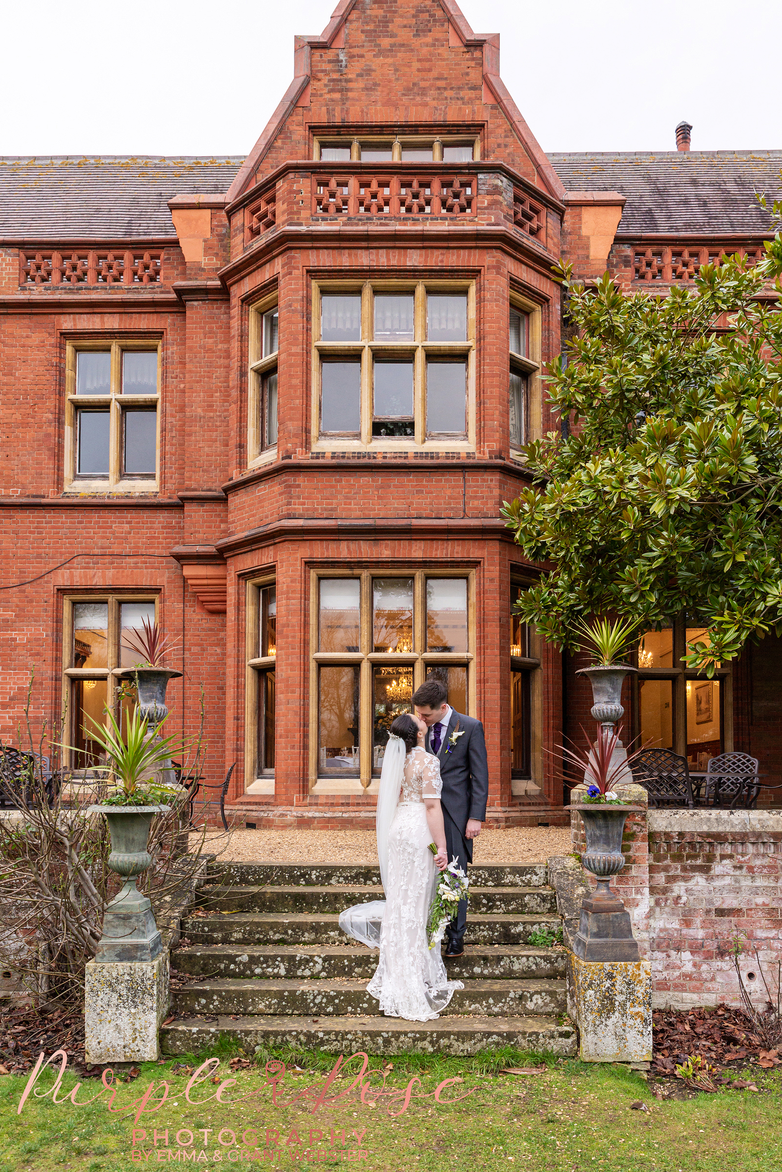 Photo of a bride and groom on the steps of Holmewood Hall Peterborough