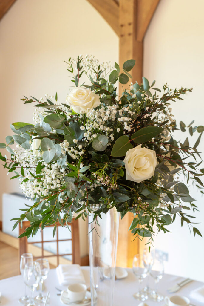 Flowers in a tall vase as a wedding breakfast centre piece