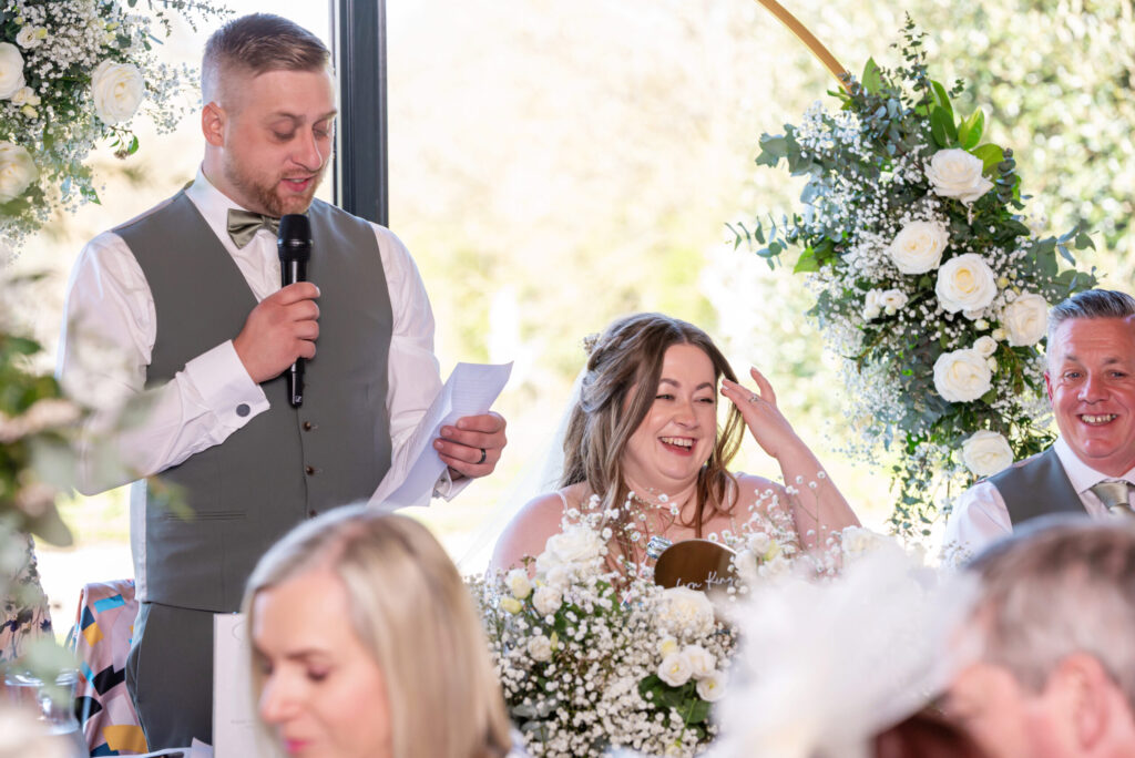 Bride and groom laughing during their wedding speeches at Dodford Manor