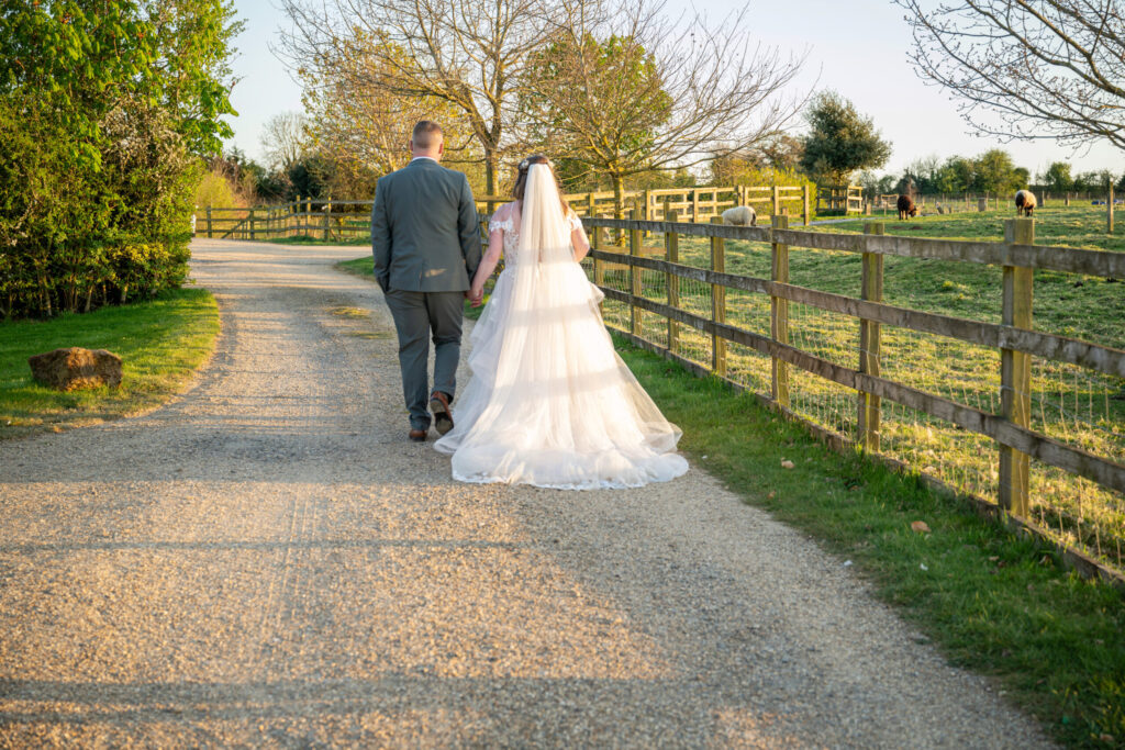 Bride and groom walking away hand in hand down the driveway at Dodford Manor on their wedding day